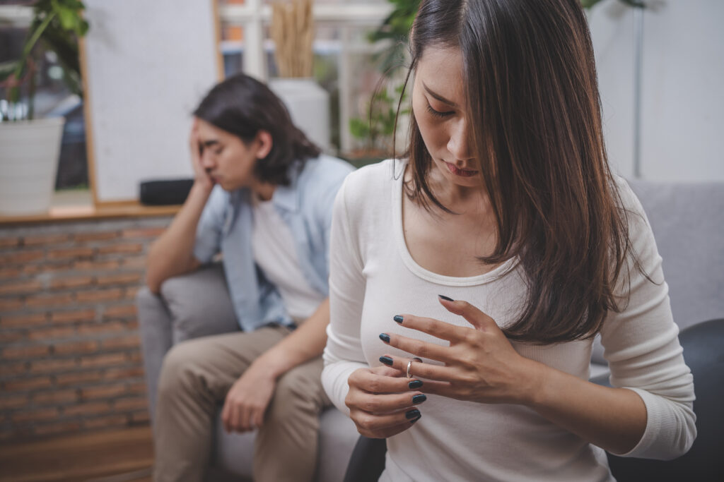 A woman looking sad taking off her wedding ring